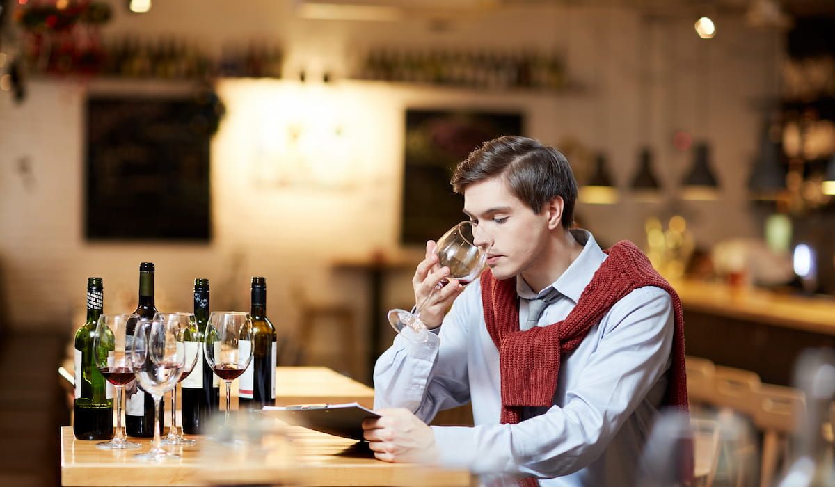 Young sommelier with wineglass tasting several sorts of red wine