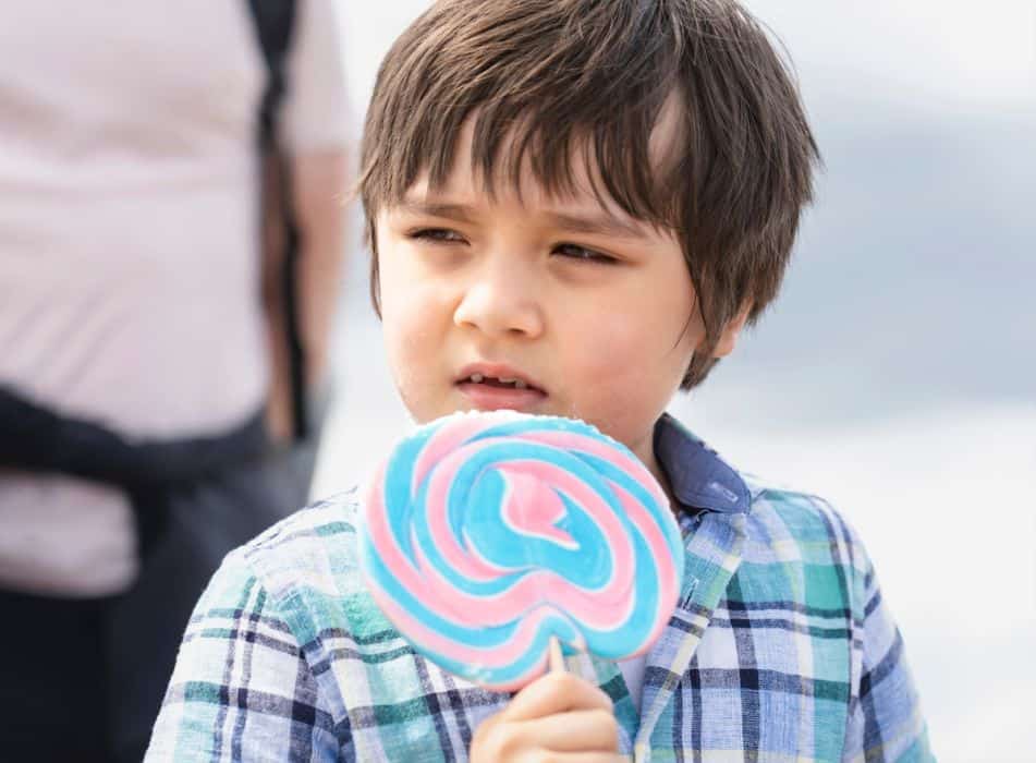little boy holding a sweet lollipop in the park