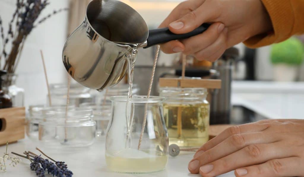 pouring melted wax onto a glass to make homemade candles