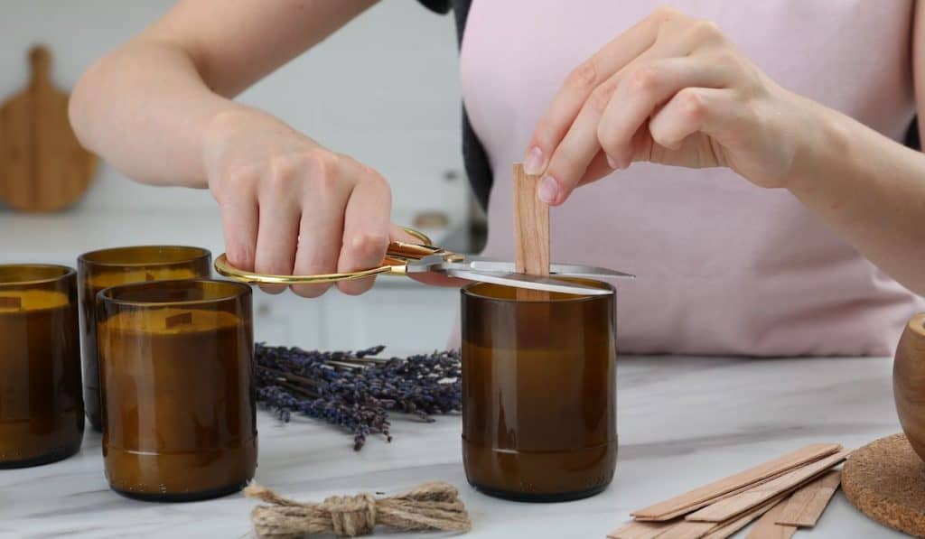 woman cutting a wooden wick to finish a candle