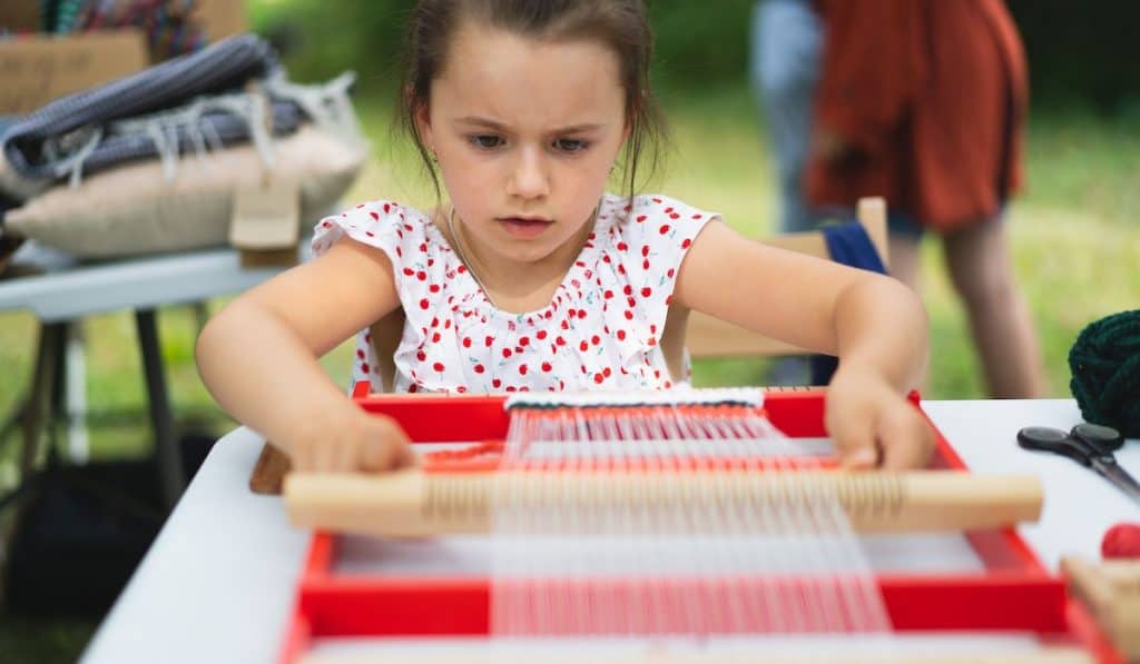 young girl focused on weaving