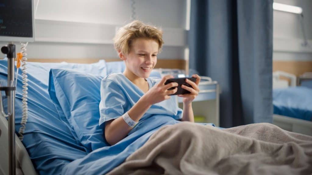 A young boy confined in the hospital playing video game on his phone