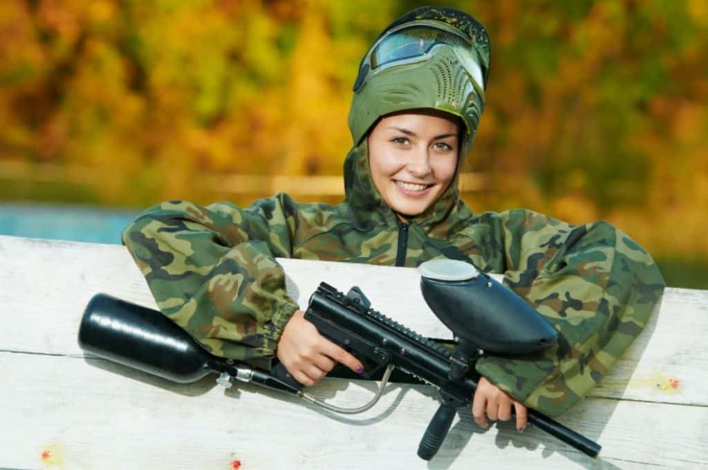 a teenage girl playing paintball outdoors