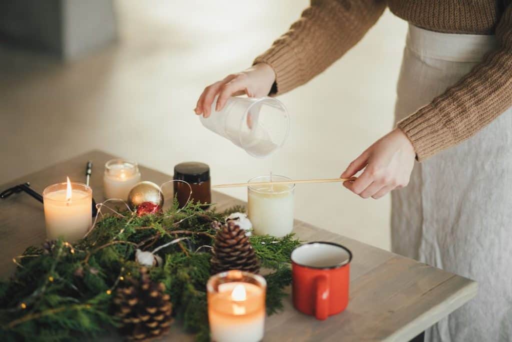a woman pouring wax to make candles on top of the table