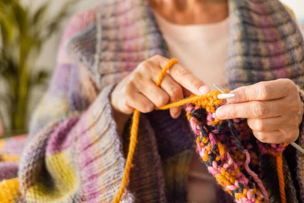 an elder woman knitting a scarf as a hobby