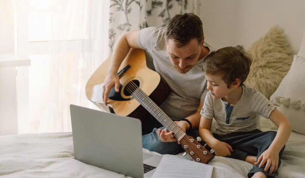 dad teaching son to play the guitar