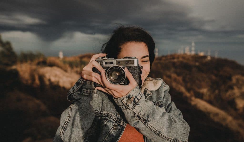 happy young woman holding a vintage camera