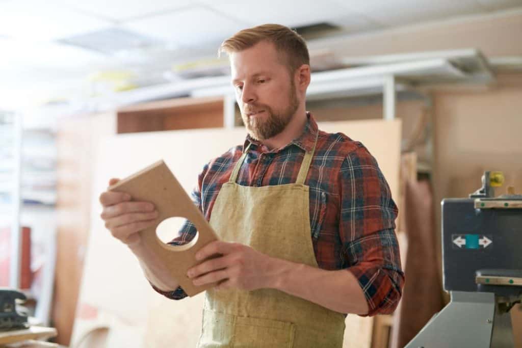 man holding carved wood in a workshop