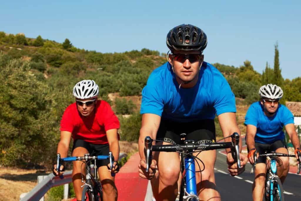 three men cycling at the side of the road