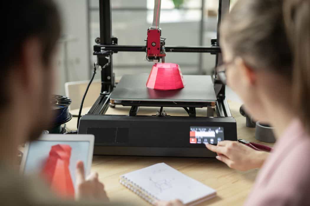 two people watching machine while 3D printing