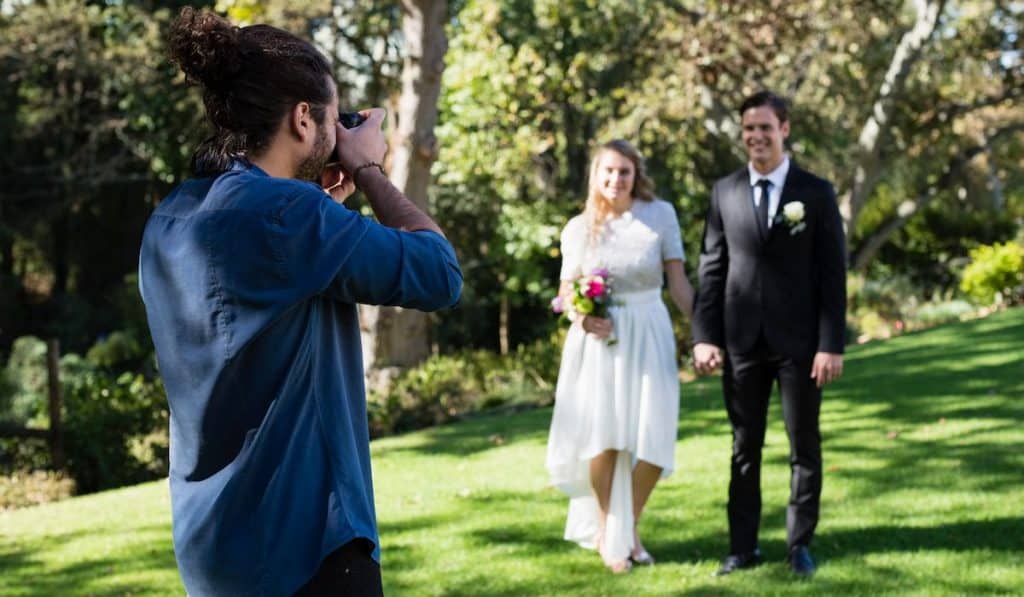 wedding photographer taking photo of newly a newly wed couple