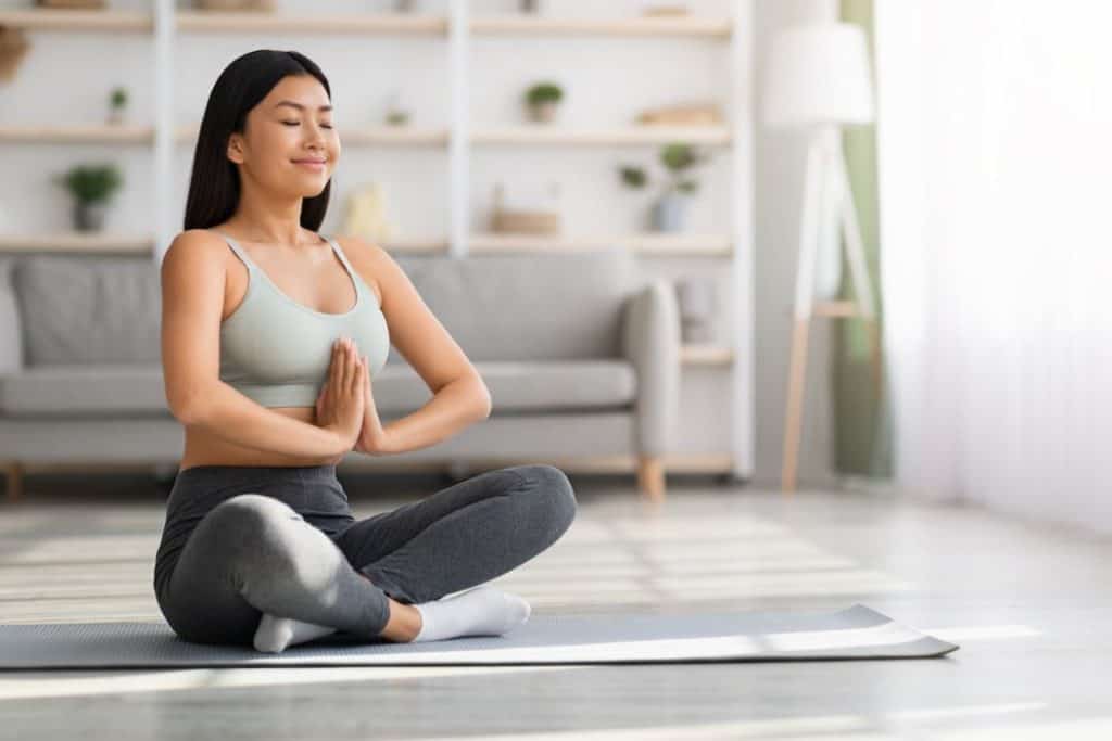 young woman meditating in the morning on her yoga mat