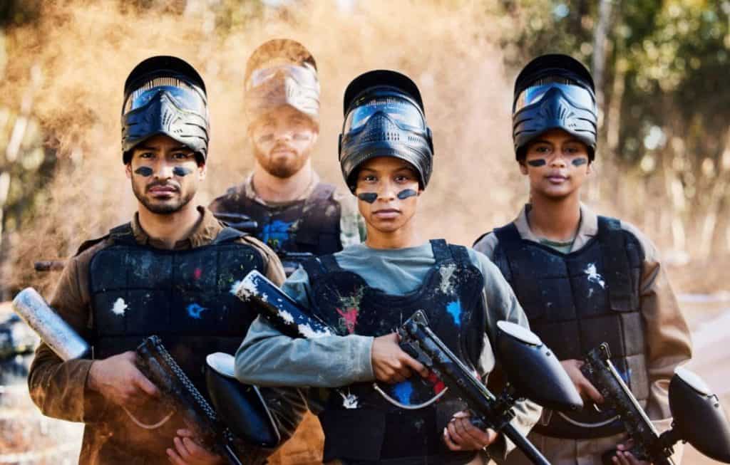 A team of four people wearing vest during paintball gun fight