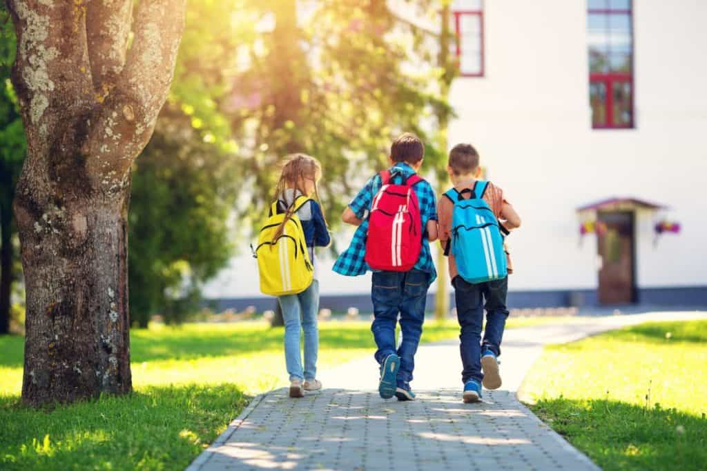 Children walking home from school carrying their backpacks 