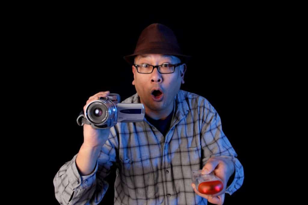 a ghost hunter holding a camcorder and ghost hunting equipment