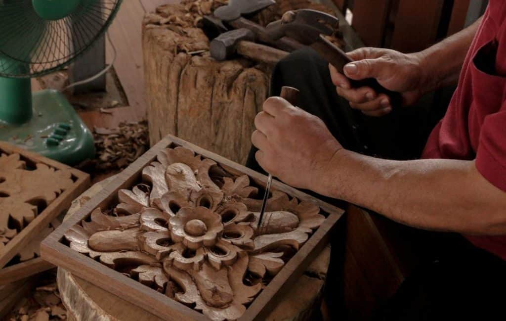 a man carving wood using chisel and mallet