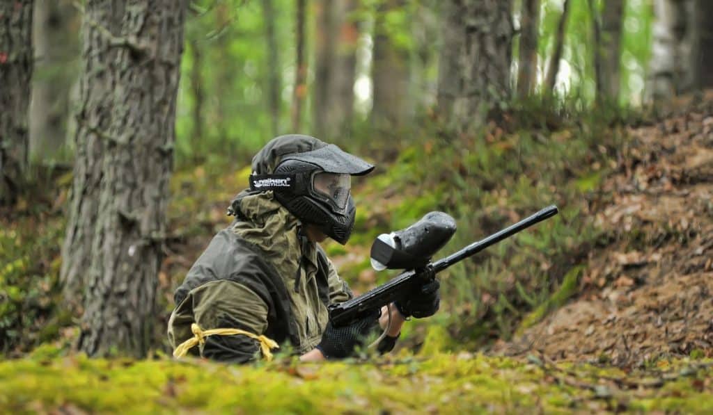 an airsoft player peeking from a shallow trench