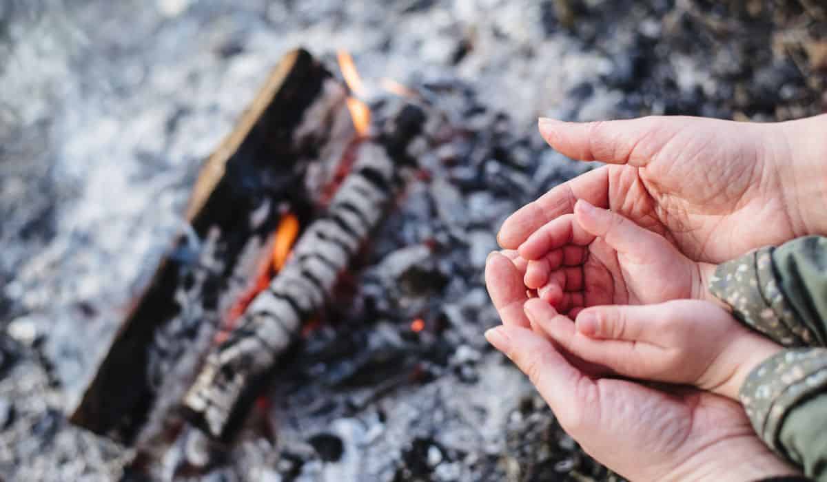 an adult and baby hands near a camp fire