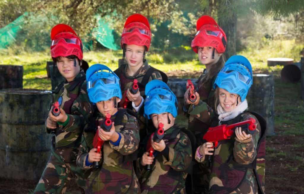 A group of kids in gear holding their paintball guns ready for a friendly battle