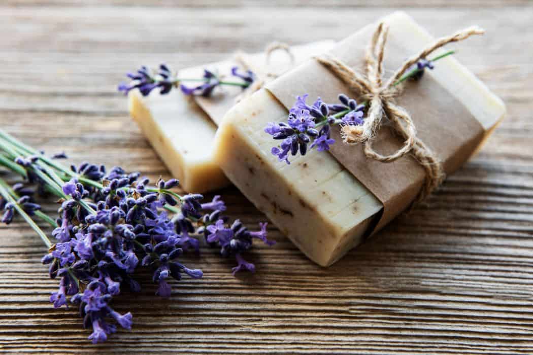 Bars of handmade soap with lavender flowers over wood grunge background
