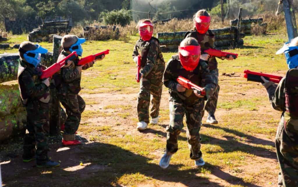 Kids playing paintball gun fight in the field