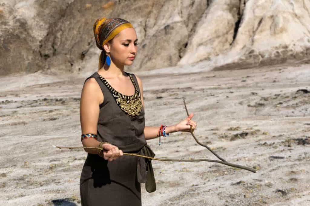 a girl in black holding a Y-shaped rod