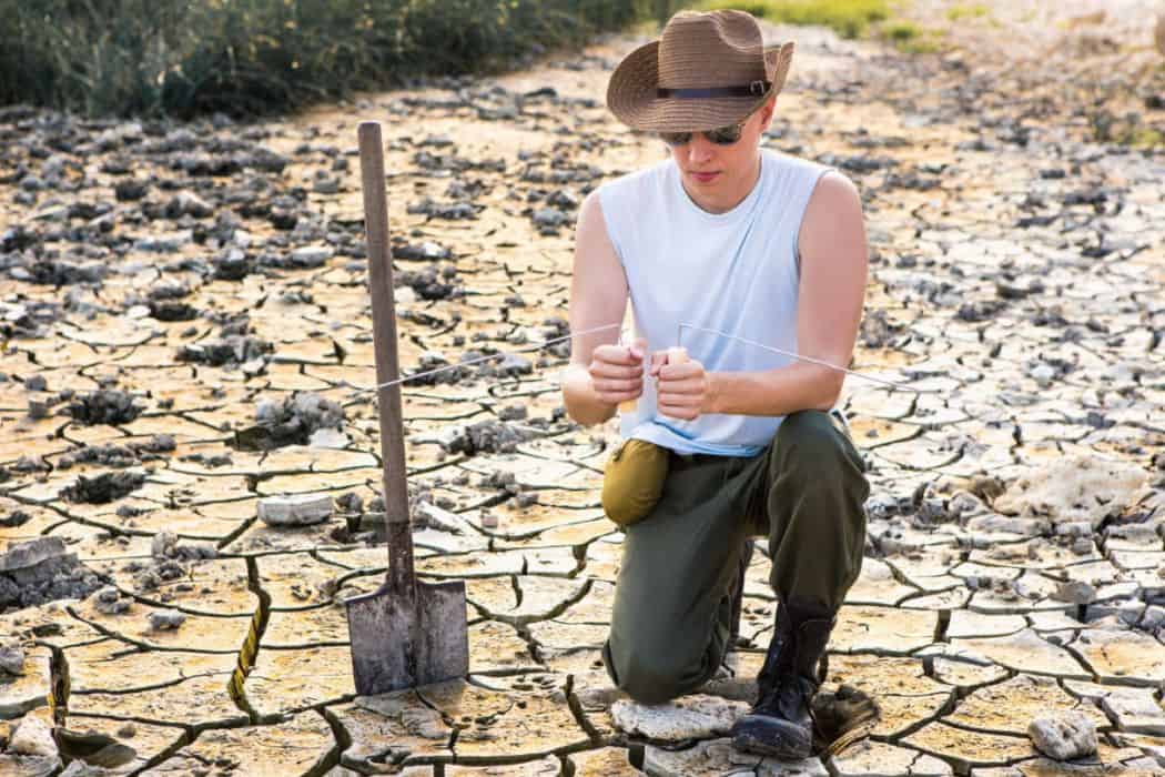 a man searching for water in a dry land using an L-shape rods