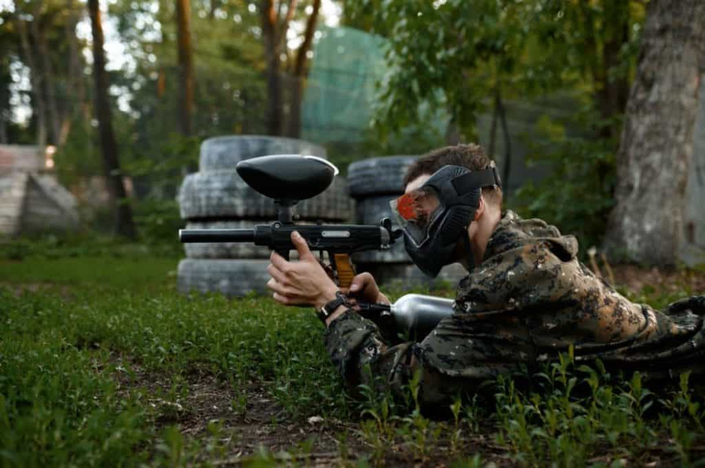a paintball player proning and waiting for an opportunity to shoot