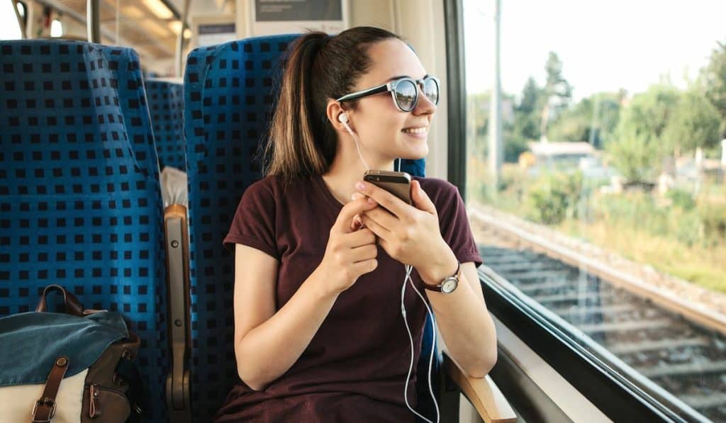 a young woman traveling by train listening to a podcast
