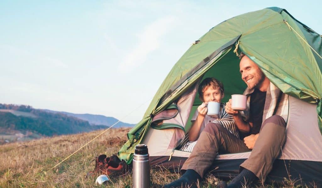 father and son duo drinking a hot beverage at sunrise