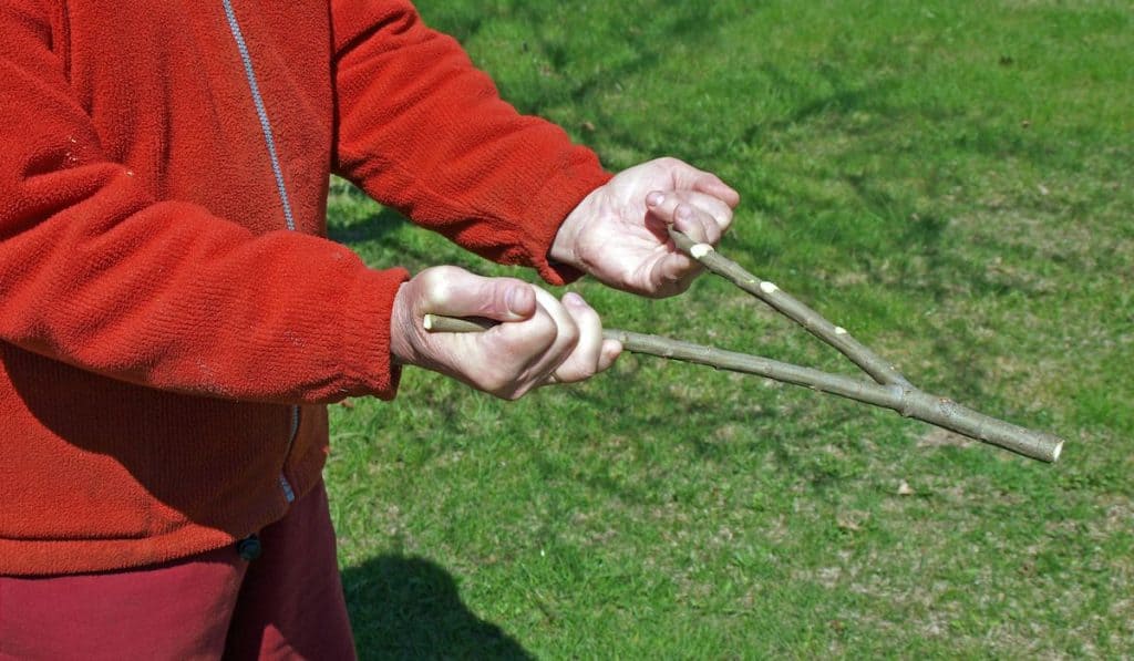 man with a red sweater holding a y shaped rod