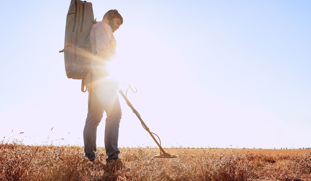 photo of a man metal detecting in a field