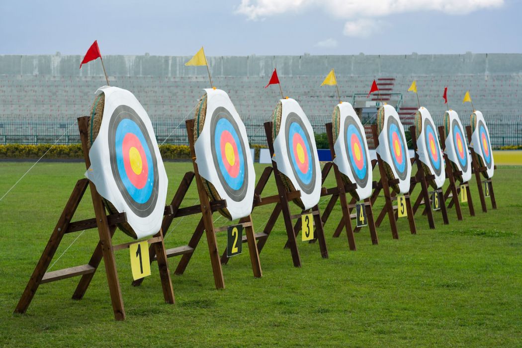 Series of straw archery targets in wooden stands inside football stadium