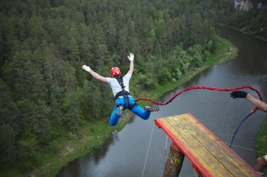 A man wearing a red helmet bungee jumping