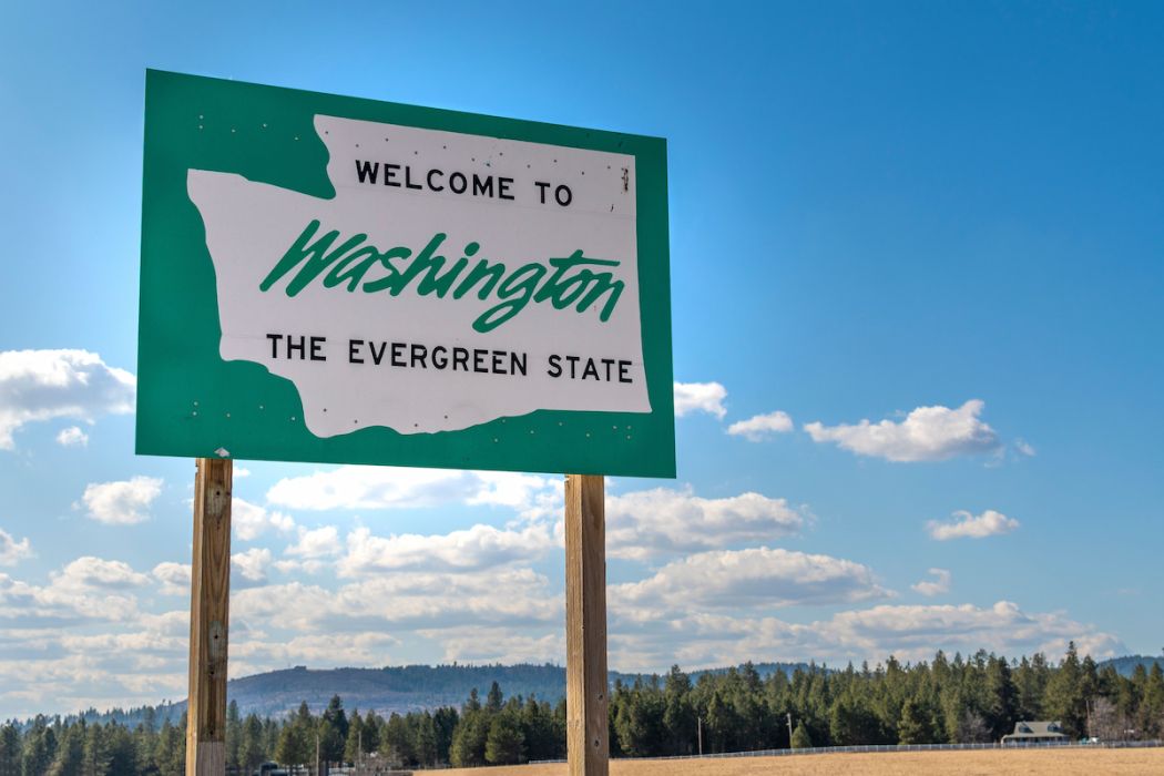 A roadside sign with welcome to Washington State