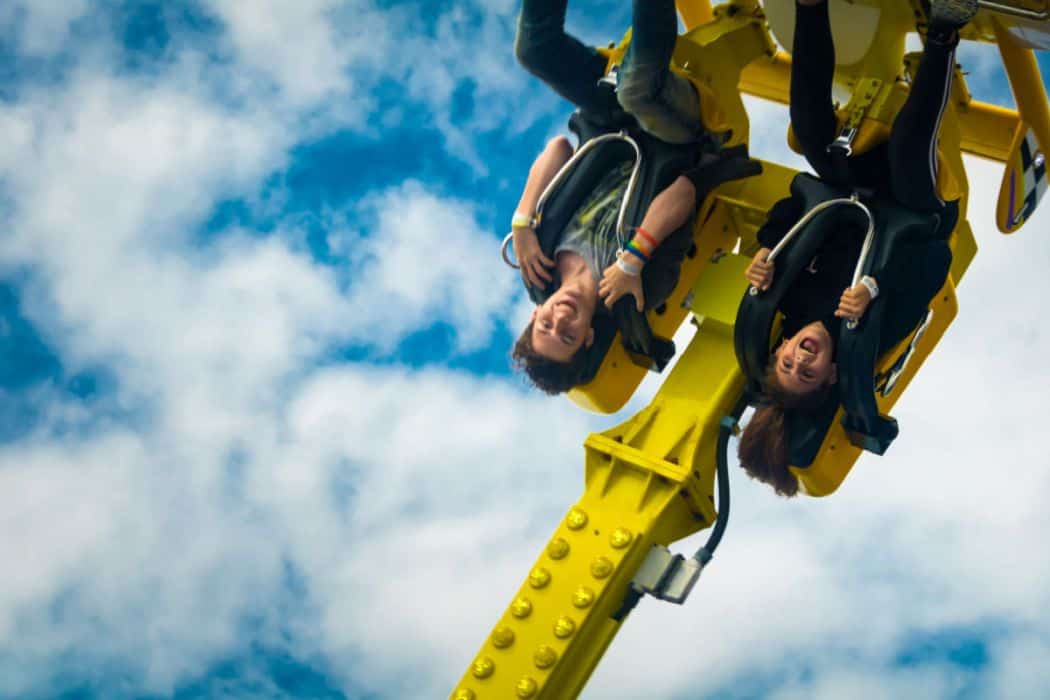 a couple upside down riding an extreme ride in a theme park