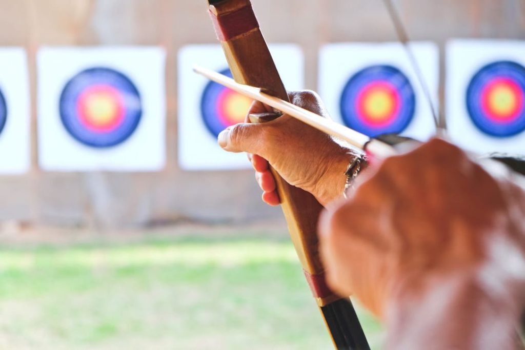 archer holds his bow aiming at a target