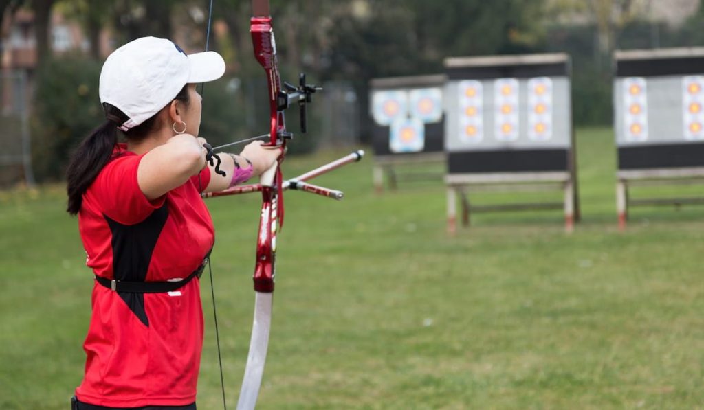 woman in red shirt practicing archery 