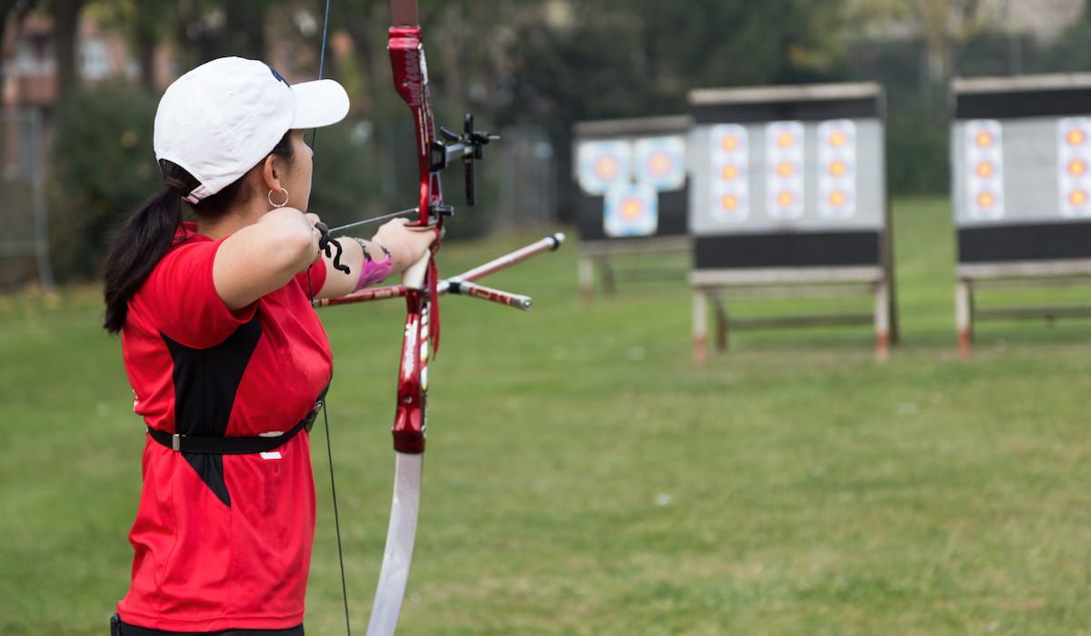 female practicing archery outdoors