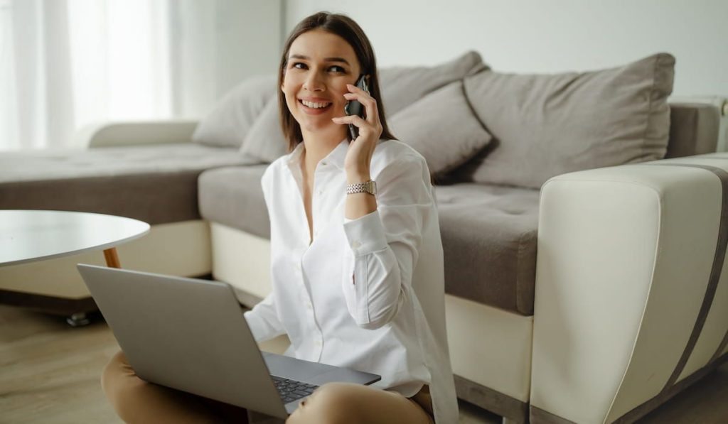 woman talking over the phone with laptop on her lap