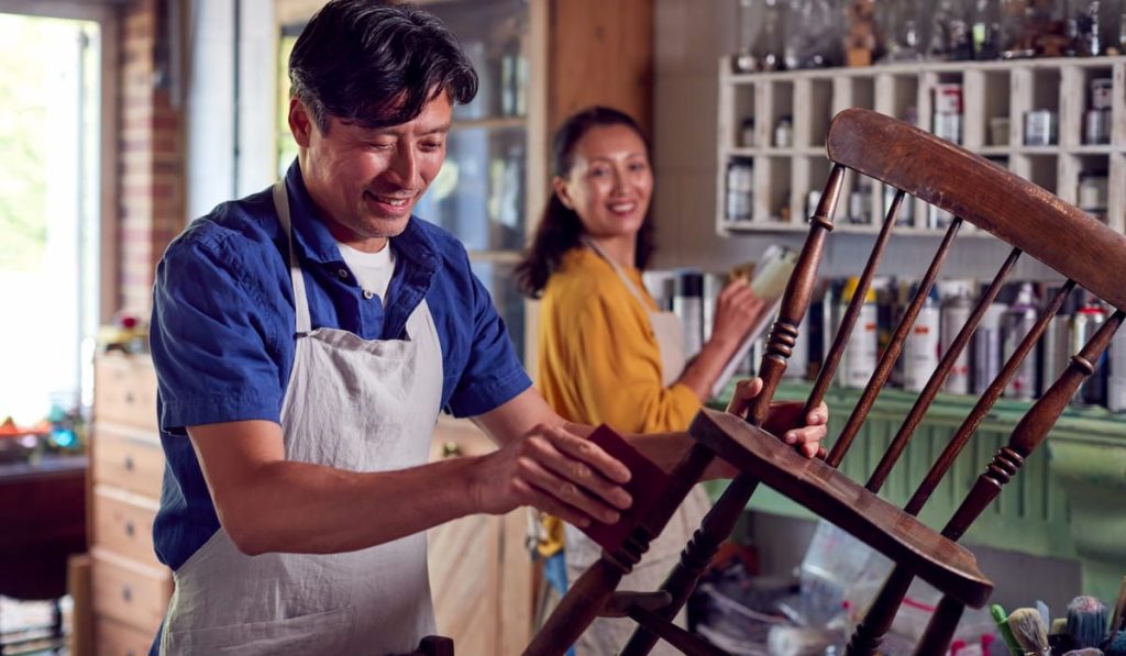 man restoring furniture in workshop at home 