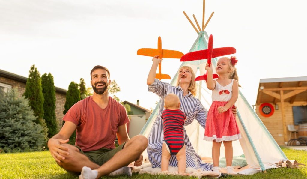 parents playing with children while camping in the backyard 