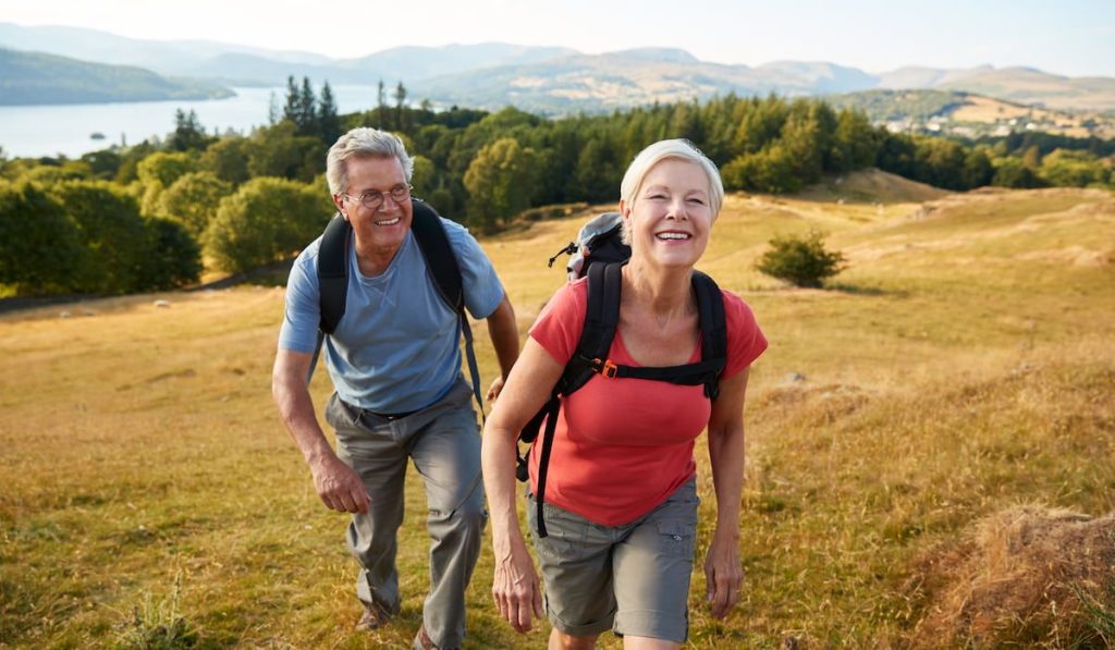 senior couple climbing hill on hike