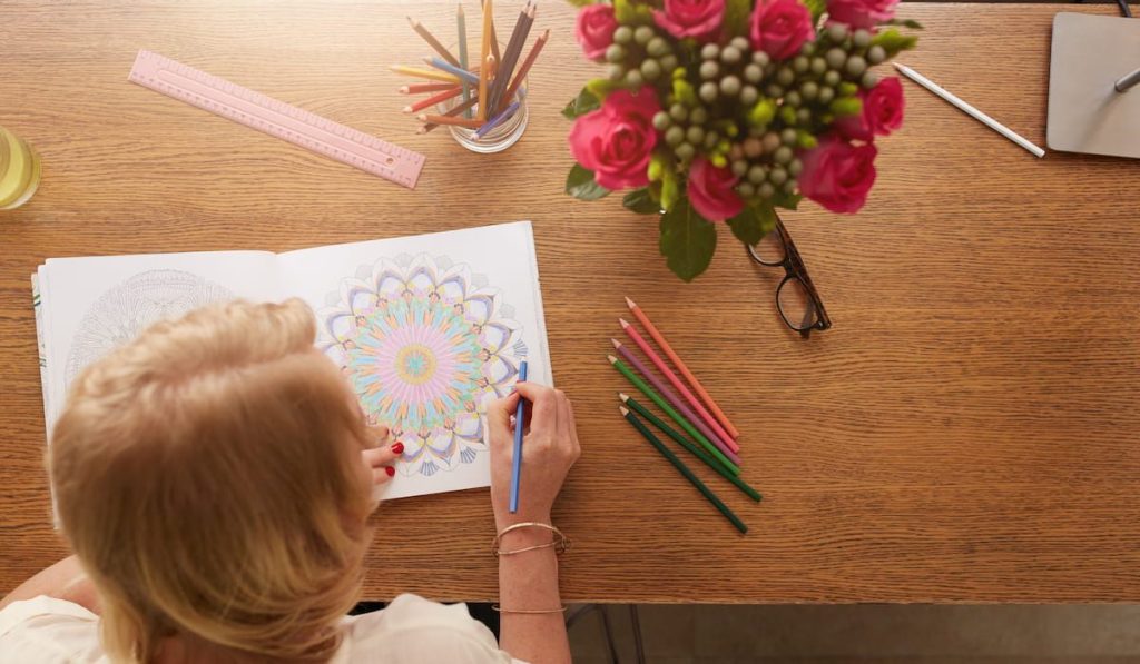 woman coloring an adult coloring book using color pencils
