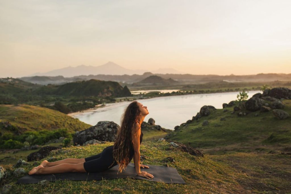 Woman training outdoors on yoga mat at sunrise