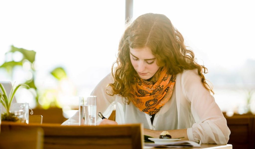 woman in a cafe jotting down her thoughts