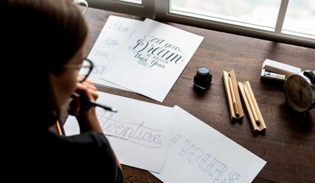 female calligraphist looking at her calligraphic artwork on the table