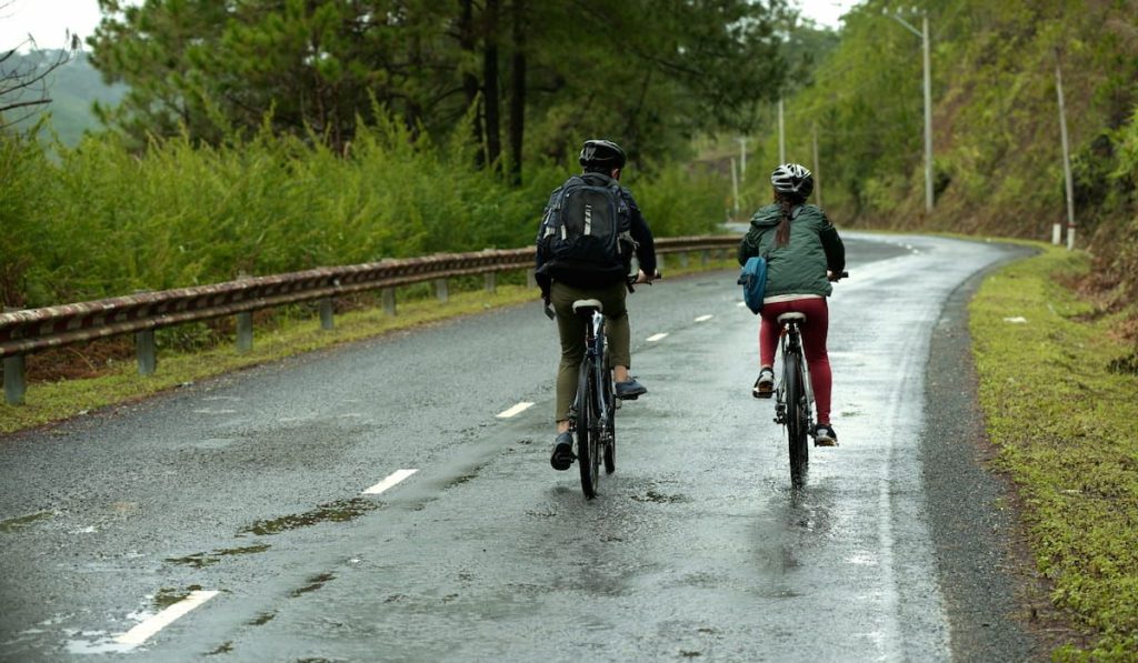 couple cycling together down wet road