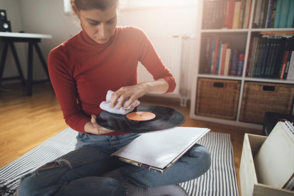 girl cleaning dust form her vinyl record collection 