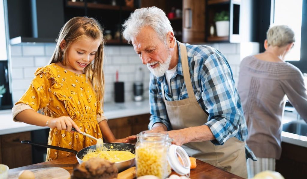 grandfather helping children to cook in the kitchen 